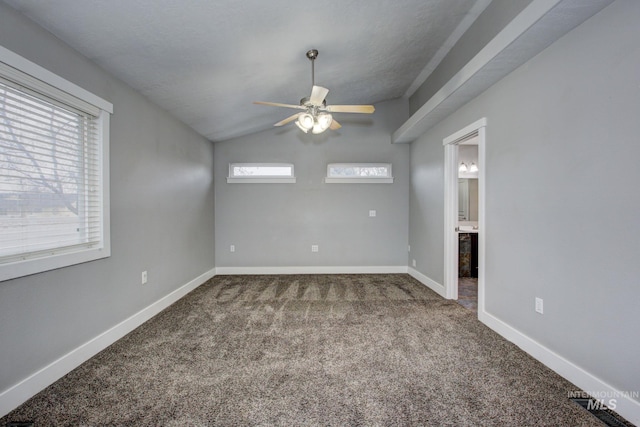 carpeted empty room with a healthy amount of sunlight, lofted ceiling, baseboards, and ceiling fan