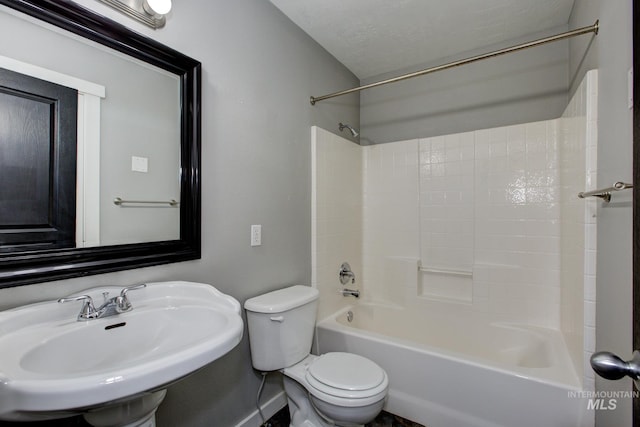 full bathroom featuring a sink, shower / bathing tub combination, toilet, and a textured ceiling