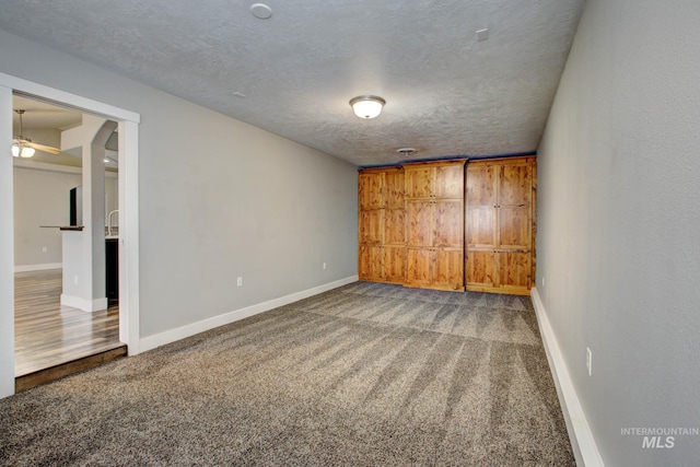 unfurnished bedroom with baseboards, a textured ceiling, and carpet