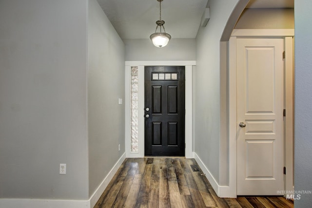 entryway with baseboards, arched walkways, and dark wood-style flooring