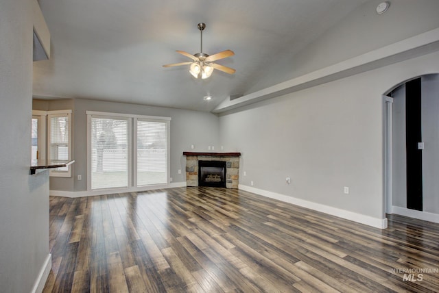 unfurnished living room featuring dark wood-type flooring, baseboards, lofted ceiling, a fireplace, and arched walkways