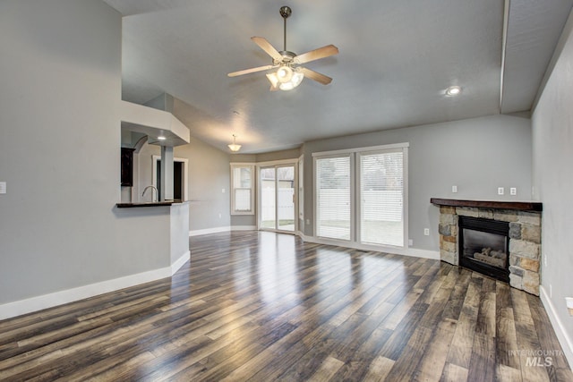 unfurnished living room with a fireplace, lofted ceiling, dark wood-style floors, and baseboards