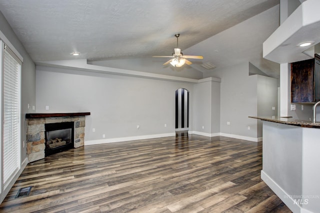 unfurnished living room with a fireplace, dark wood-type flooring, a ceiling fan, and vaulted ceiling