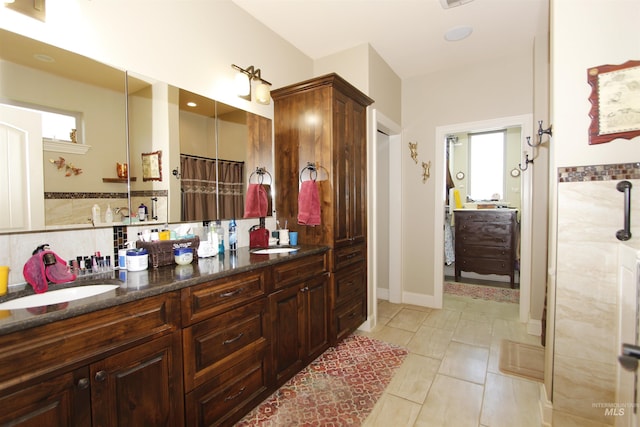 full bath with double vanity, a sink, and a healthy amount of sunlight