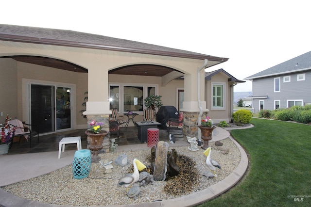 rear view of property featuring a yard, a patio, and stucco siding
