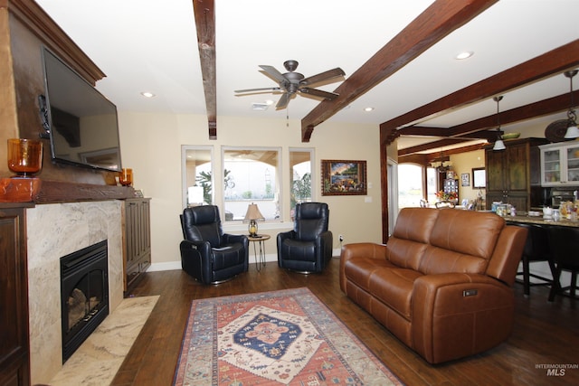 living room featuring a ceiling fan, beam ceiling, baseboards, dark wood-style floors, and a premium fireplace