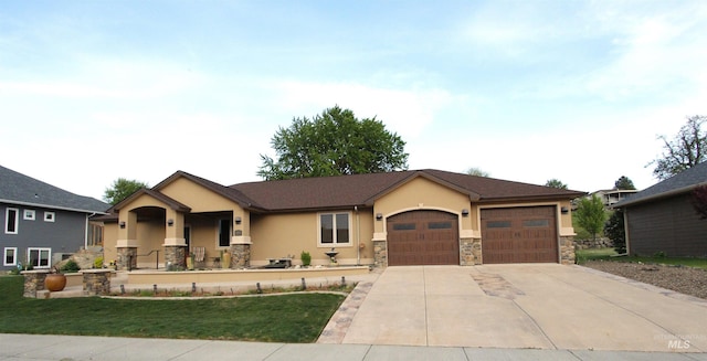 ranch-style house featuring an attached garage, driveway, stone siding, and stucco siding