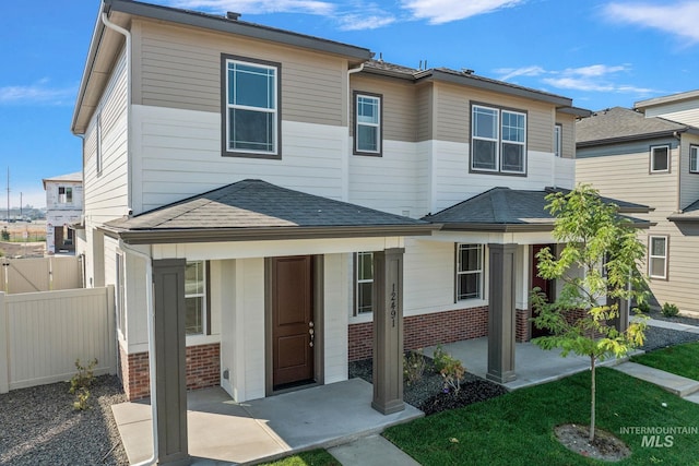 townhome / multi-family property featuring brick siding, a shingled roof, and fence