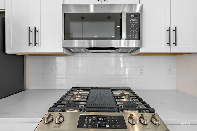 kitchen featuring appliances with stainless steel finishes, white cabinets, backsplash, and light stone countertops