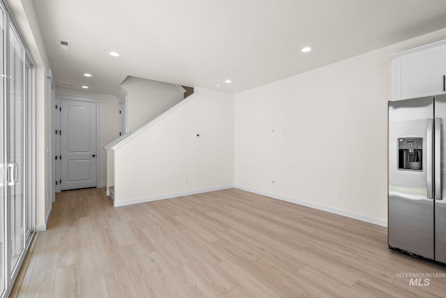 unfurnished living room with baseboards, visible vents, light wood-style flooring, stairs, and recessed lighting