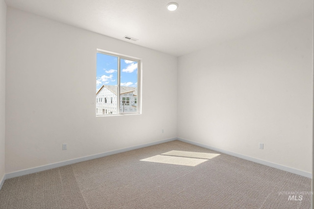 carpeted empty room featuring visible vents and baseboards