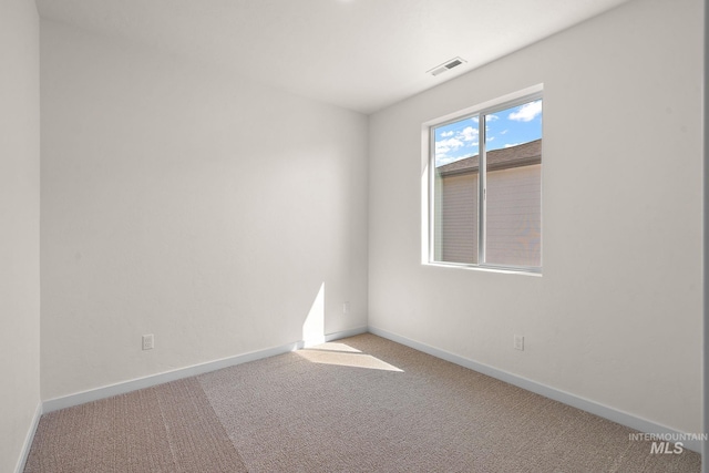 carpeted empty room featuring baseboards and visible vents