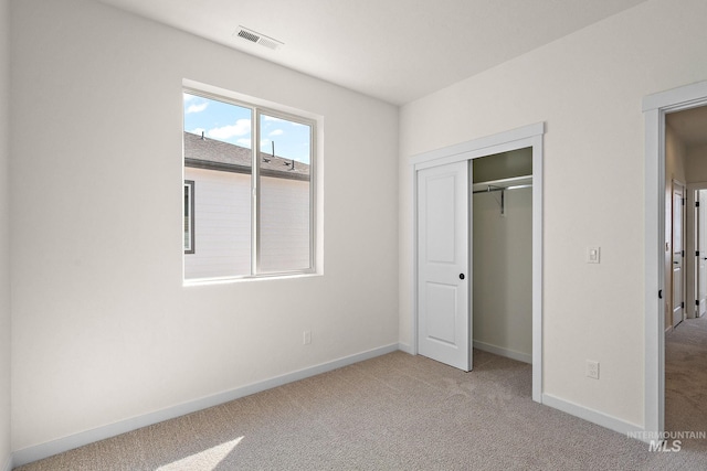 unfurnished bedroom with light carpet, visible vents, baseboards, and a closet