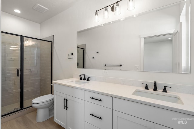 full bathroom featuring double vanity, visible vents, a sink, and wood finished floors