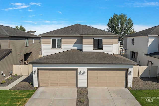 view of front of house featuring fence, concrete driveway, and roof with shingles