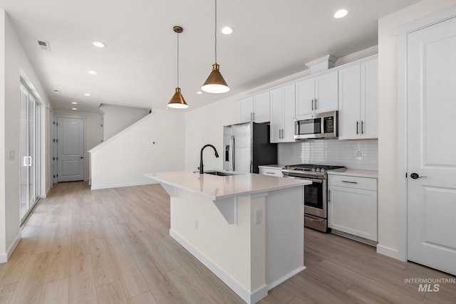 kitchen featuring white cabinetry, stainless steel appliances, light countertops, and decorative light fixtures