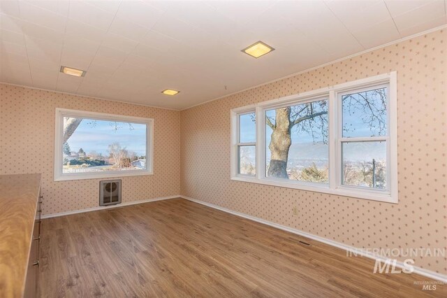1605 Vineyard Dr, Lewiston, ID 83501 - empty room with wood finished floors, wallpapered walls, heating unit, and crown molding