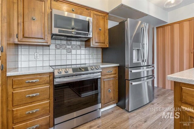 1605 Vineyard Dr, Lewiston, ID 83501 - kitchen with appliances with stainless steel finishes, brown cabinetry, light wood-type flooring, and decorative backsplash