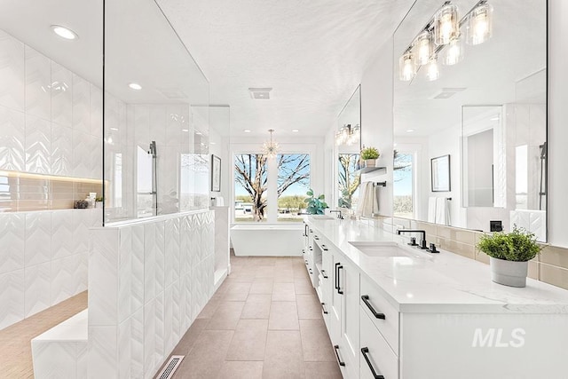 full bathroom featuring a sink, a soaking tub, tile patterned floors, double vanity, and walk in shower