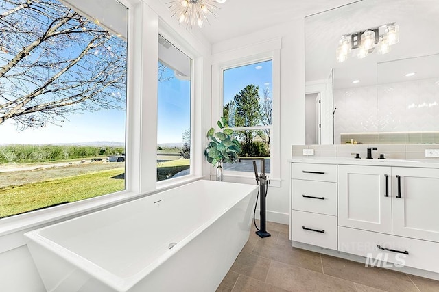 full bath featuring tasteful backsplash, tile patterned flooring, a soaking tub, and vanity