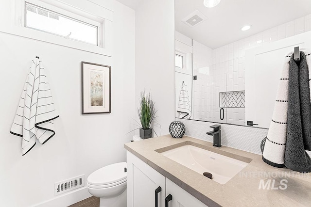 full bath with a shower stall, visible vents, vanity, and toilet