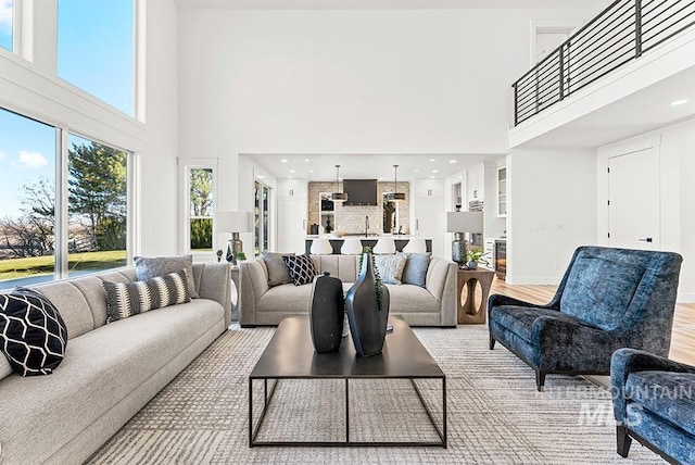 living room featuring a towering ceiling, light wood-style floors, and baseboards