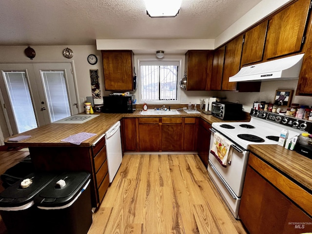 kitchen with sink, a textured ceiling, light wood-type flooring, kitchen peninsula, and white appliances