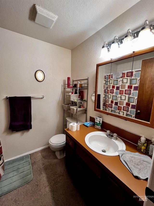 bathroom with vanity, toilet, and a textured ceiling