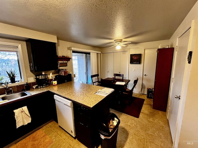 kitchen featuring sink, dishwasher, ceiling fan, a textured ceiling, and kitchen peninsula