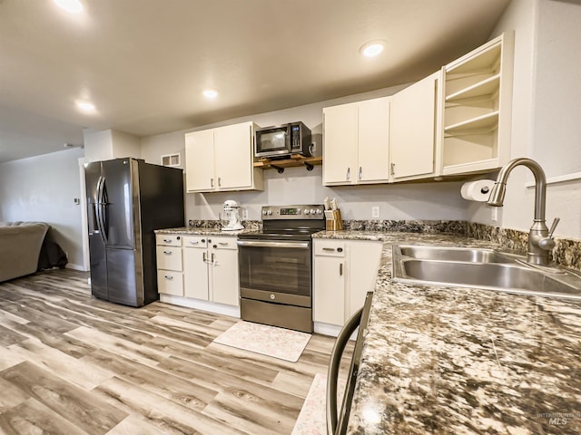 kitchen with white cabinetry, open shelves, light wood-type flooring, a sink, and appliances with stainless steel finishes