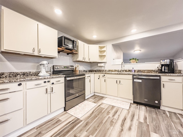 kitchen with light wood finished floors, stainless steel appliances, white cabinetry, a sink, and open shelves