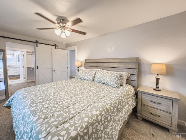 carpeted bedroom with a barn door and ceiling fan