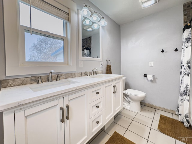 full bathroom featuring double vanity, a sink, tile patterned floors, and toilet
