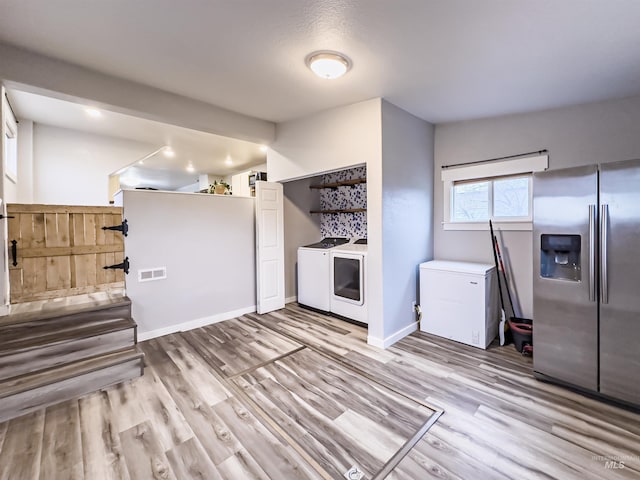 kitchen with stainless steel fridge with ice dispenser, visible vents, washer and dryer, and wood finished floors