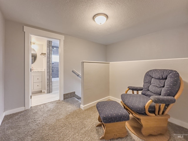 sitting room with baseboards, an upstairs landing, carpet, and a textured ceiling