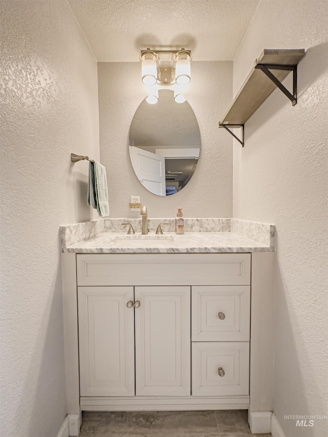 bathroom featuring vanity, a textured wall, and a textured ceiling