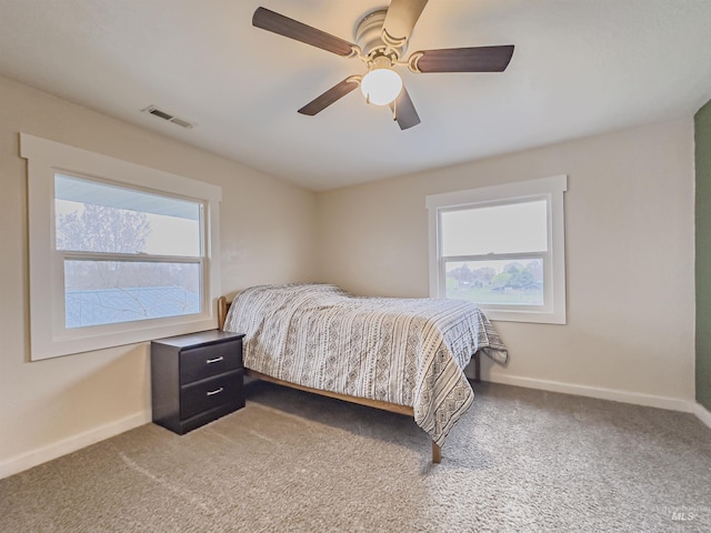 bedroom featuring baseboards, visible vents, light colored carpet, and ceiling fan