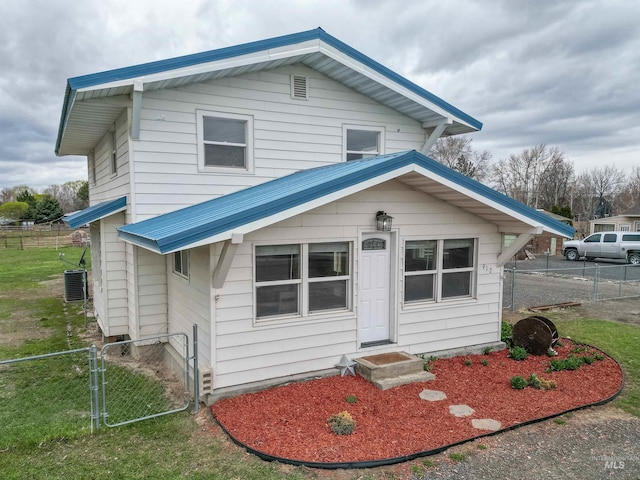view of front of home featuring a front lawn, a gate, fence, and central AC
