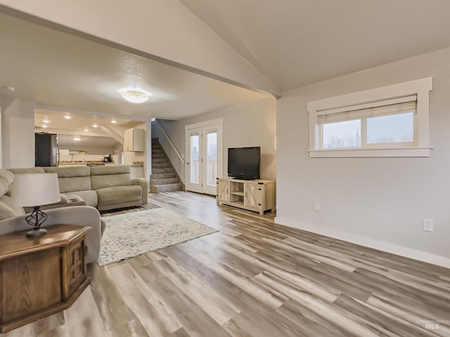 living room with baseboards, stairway, vaulted ceiling, and wood finished floors