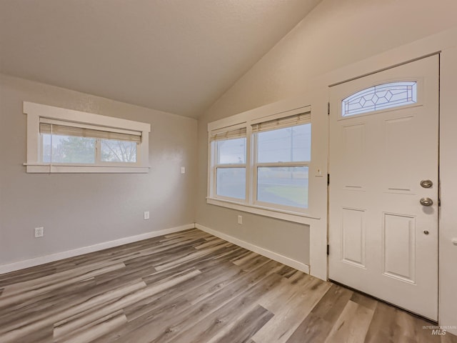 foyer with baseboards, vaulted ceiling, and light wood-type flooring