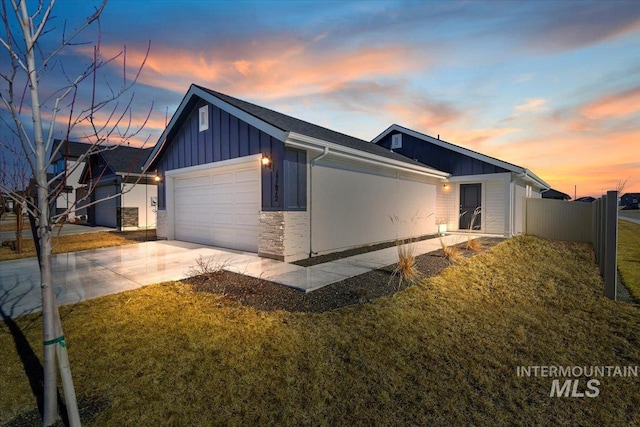 property exterior at dusk featuring a lawn, concrete driveway, an attached garage, fence, and board and batten siding