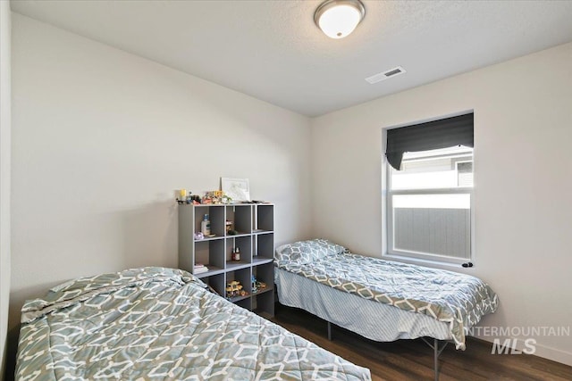 bedroom featuring visible vents, a textured ceiling, and wood finished floors