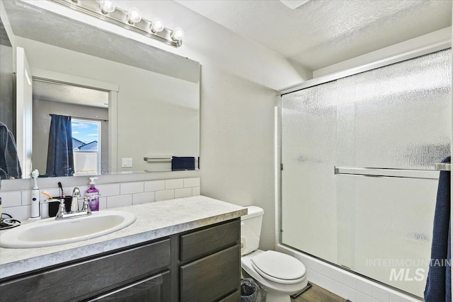 bathroom with a stall shower, vanity, toilet, and a textured ceiling