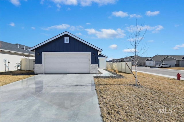 view of front facade featuring concrete driveway, a residential view, an attached garage, fence, and board and batten siding