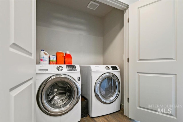 laundry area with laundry area, dark wood-type flooring, visible vents, and washer and dryer