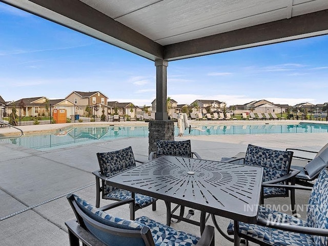 view of patio / terrace with a residential view, outdoor dining area, fence, and a community pool