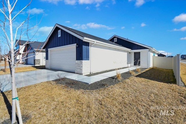 view of property exterior featuring a garage, concrete driveway, stone siding, fence, and board and batten siding