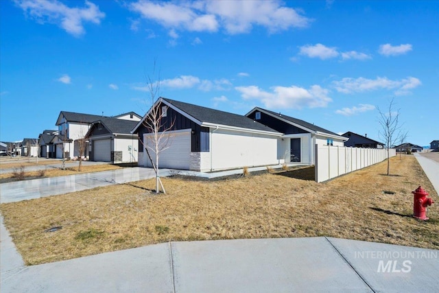 view of side of home featuring a garage, fence, driveway, a residential view, and board and batten siding