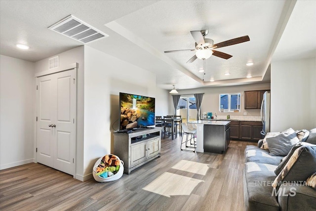 living room with visible vents, ceiling fan, baseboards, and wood finished floors