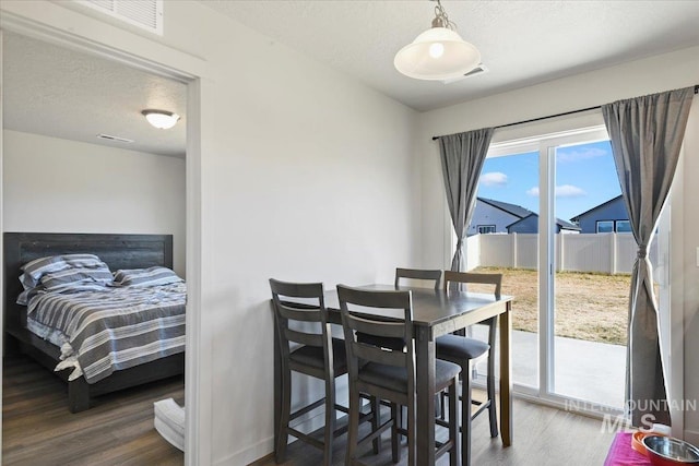 dining area with a textured ceiling, baseboards, and wood finished floors